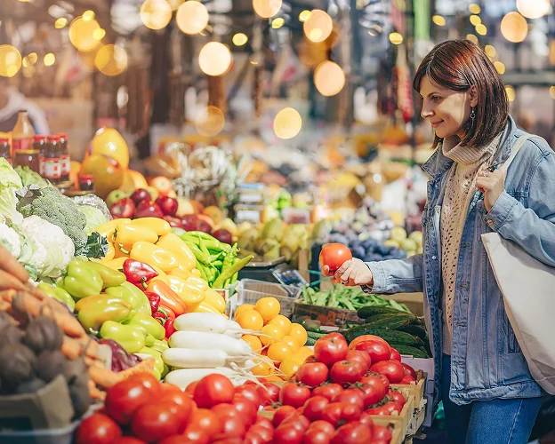femme entrain de choisir ses tomates dans un magasin de légumes